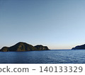 平靜的夏日海面，遠處隱約可見一座島嶼的輪廓。 140133329