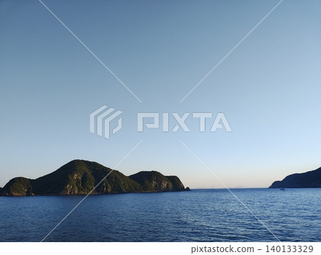 平靜的夏日海面,遠處隱約可見一座島嶼的輪廓。 平靜的夏日海面,遠處隱約可見一座島嶼的輪廓。 140133329
