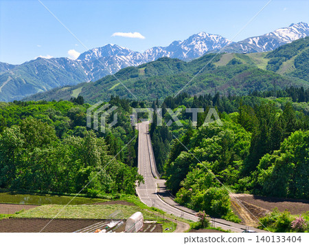 Tsugaike Panorama Park, enveloped in fresh greenery, and the snow-capped Hakuba mountain range in Otari Village, Nagano Prefecture (aerial photograph taken by drone). Tsugaike Panorama Park, enveloped in fresh greenery, and the snow-capped Hakuba mountain range in Otari Village, Nagano Prefecture (aerial photograph taken by drone). 140133404