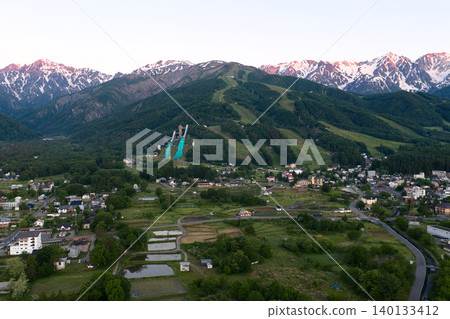 The beautiful morning glow over the Hakuba mountain range and the lush greenery of Hakuba Village, Nagano Prefecture (aerial photography by drone) The beautiful morning glow over the Hakuba mountain range and the lush greenery of Hakuba Village, Nagano Prefecture (aerial photography by drone) 140133412
