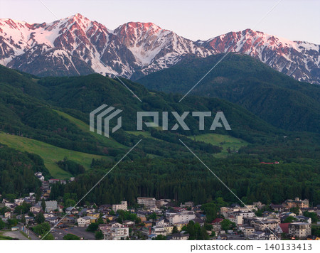 The beautiful morning glow over the Hakuba Three Peaks and the lush greenery of Hakuba Village, Nagano Prefecture (aerial photography by drone) The beautiful morning glow over the Hakuba Three Peaks and the lush greenery of Hakuba Village, Nagano Prefecture (aerial photography by drone) 140133413