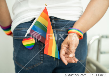 Woman holding LGBT rainbow colorful flag, symbol of lesbian, gay, bisexual, transgender, human rights, tolerance and peace. 140133835