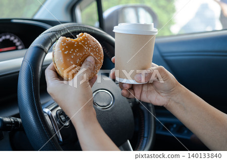 Asian lady holding ice coffee and bread bakery food in car dangerous and risk an accident. Asian lady holding ice coffee and bread bakery food in car dangerous and risk an accident. 140133840