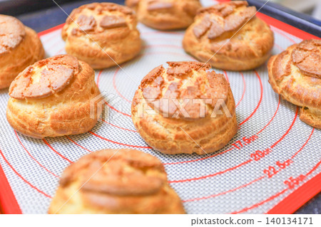 A picture of freshly baked cookie choux pastry dough lined up after being taken out of the oven. A picture of freshly baked cookie choux pastry dough lined up after being taken out of the oven. 140134171