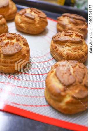 A picture of freshly baked cookie choux pastry dough lined up after being taken out of the oven. A picture of freshly baked cookie choux pastry dough lined up after being taken out of the oven. 140134172