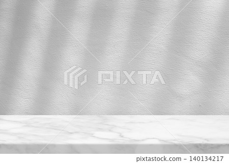 White Marble Table Set Against White Stucco Wall with Light Beam and Shadow White Marble Table Set Against White Stucco Wall with Light Beam and Shadow 140134217