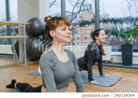 Women practicing yoga stretches in fitness studio Women practicing yoga stretches in fitness studio 140134364