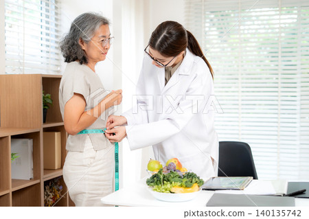 Nutritionist examining senior woman for weightloss planning for health in clinic office. 140135742