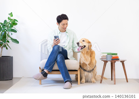 寵物：金毛尋回犬 - 一名男子和他的狗在客廳放鬆。 140136101