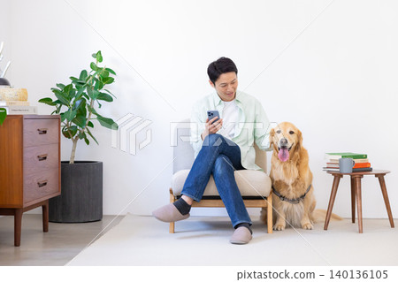 寵物:金毛尋回犬 - 一名男子和他的狗在客廳放鬆。 寵物:金毛尋回犬 - 一名男子和他的狗在客廳放鬆。 140136105