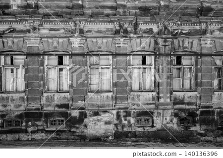 Dilapidated historic brick building with broken windows and crumbling details 140136396