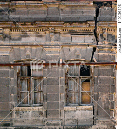 Weathered building facade with broken windows and structural cracks Weathered building facade with broken windows and structural cracks 140136398