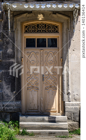 Weathered stone archway frames a vintage wooden door with decorative panels Weathered stone archway frames a vintage wooden door with decorative panels 140136414