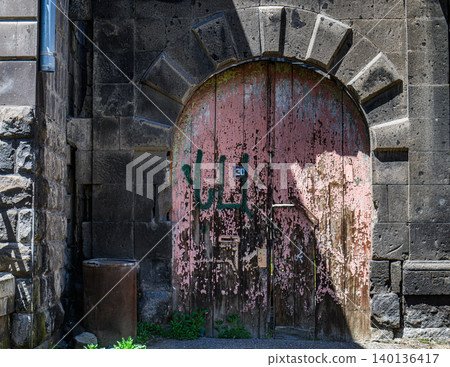 Old arched door with rusted metal and faded paint 140136417