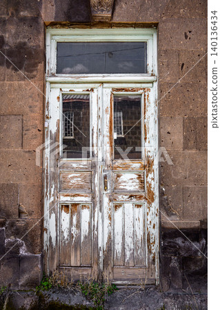 Old, peeling white door set in stone wall Old, peeling white door set in stone wall 140136434