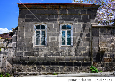 Weathered gray stone building with arched windows Weathered gray stone building with arched windows 140136435