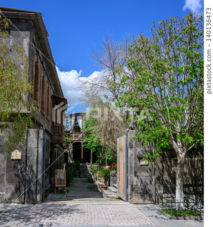 Narrow alleyway through historic stone buildings with trees and clear sky Narrow alleyway through historic stone buildings with trees and clear sky 140136473