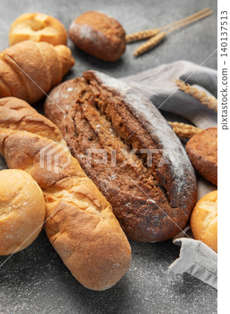 Freshly baked bread assortment with wheat ears on rustic background Freshly baked bread assortment with wheat ears on rustic background 140137513
