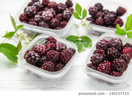 Frozen blackberries in containers on white wooden table Frozen blackberries in containers on white wooden table 140137533