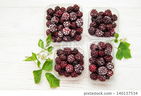 Frozen blackberries in containers on white wooden table Frozen blackberries in containers on white wooden table 140137534