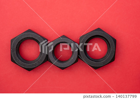 Hexagonal bolt and nut on a red background Hexagonal bolt and nut on a red background 140137799