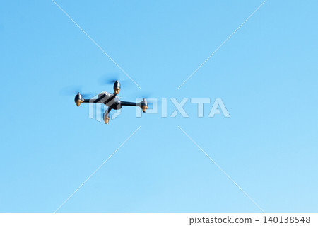 Black drone fllying in the blue sky. Innovative modern technology for work, game or entertainment. Black drone fllying in the blue sky. Innovative modern technology for work, game or entertainment. 140138548