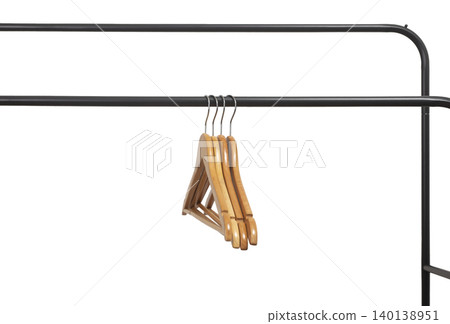 Wooden hangers hanging on black metal rack corner against white wall. Garment holders positioned on horizontal bar. Interior storage concept for wardrobe, retail, organization.. Wooden hangers hanging on black metal rack corner against white wall. Garment holders positioned on horizontal bar. Interior storage concept for wardrobe, retail, organization.. 140138951