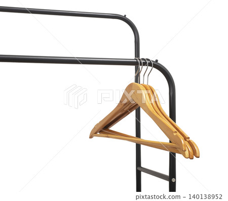 Wooden hangers hanging on black metal rack corner against white wall. Garment holders aligned on horizontal bar. Interior storage setup for wardrobe, retail, organization concept.. Wooden hangers hanging on black metal rack corner against white wall. Garment holders aligned on horizontal bar. Interior storage setup for wardrobe, retail, organization concept.. 140138952