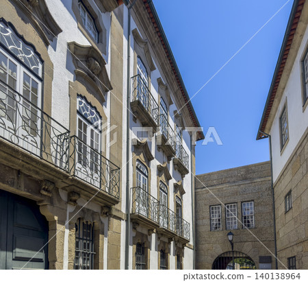 Narrow street between historic buildings in Guimaraes city center. Old architecture forms passage with windows balconies and stone walls. Travel destination concept showing European heritage Narrow street between historic buildings in Guimaraes city center. Old architecture forms passage with windows balconies and stone walls. Travel destination concept showing European heritage 140138964
