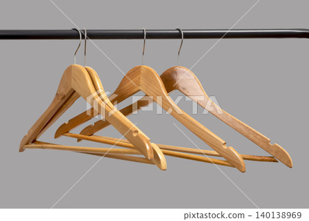 Wooden hangers hanging on black metal rack against neutral wall. Garment holders aligned on horizontal bar. Interior storage scene for wardrobe, retail, organization concept.. 140138969