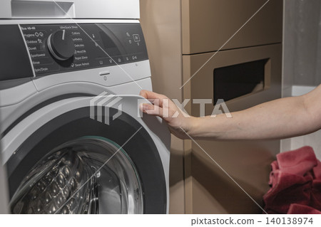 Woman touching washing machine door in laundry room. Adult female operating front loading appliance. Domestic cleaning equipment for home, household, lifestyle concept.. 140138974