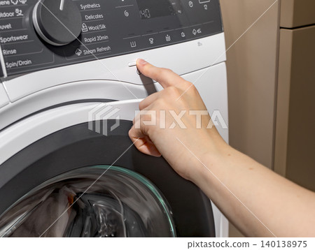 Woman touching washing machine control panel near door. Adult female pressing button on front loading appliance. Domestic cleaning concept for home, household, lifestyle.. Woman touching washing machine control panel near door. Adult female pressing button on front loading appliance. Domestic cleaning concept for home, household, lifestyle.. 140138975