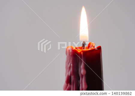 Lit red wax candle with interesting melted texture Lit red wax candle with interesting melted texture 140139862