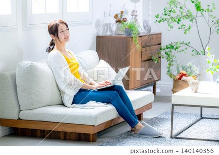 Young woman using a computer in the living room Young woman using a computer in the living room 140140356