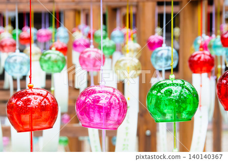 Colorful wind chimes lined up in vibrant hues, their transparency and the coolness they evoke, are a quintessential symbol of Japanese summer. 140140367