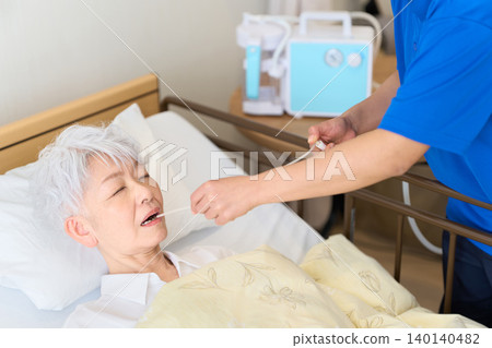Asian caregiver performing suctioning of phlegm on a senior citizen Asian caregiver performing suctioning of phlegm on a senior citizen 140140482