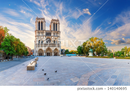 Panoramic view of Paris cityscape with the majestic Notre-Dame cathedral under a dramatic sunset sky 140140695