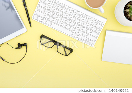 workspace with tablet, keyboard, coffee cup and eyeglasses copy space on yelow background. Top view. 140140921