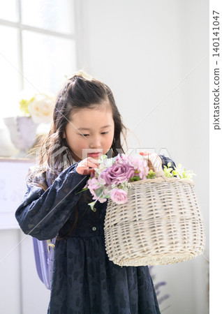 一個背著書包的日本女孩凝視著一籃花。 一個背著書包的日本女孩凝視著一籃花。 140141047