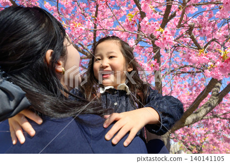 A parent and child embracing under the Kawazu cherry blossoms A parent and child embracing under the Kawazu cherry blossoms 140141105