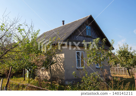 A small wooden village country house with a triangular roof. An old hut with a garden plot. 140141211