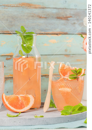 Grapefruit juice with mint in glasses on the table. Refreshing summer cocktail. Grapefruit juice with mint in glasses on the table. Refreshing summer cocktail. 140141372