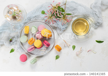 Colorful french macaroon cakes. Macaroons with jasmine flowers and tea on white table background. Selective focus 140141385