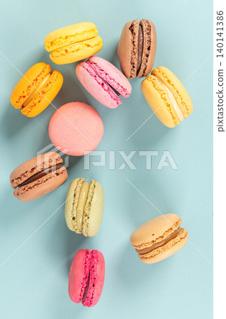 Cake macaron or macaroon on turquoise background from above, colorful almond cookies, pastel colors, vintage card, top view 140141386