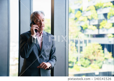 Senior male executive talking on smartphone in modern office Senior male executive talking on smartphone in modern office 140141526