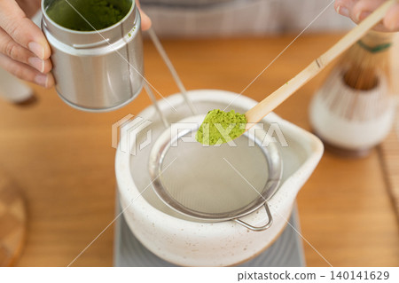 Woman whisking Matcha green tea with bamboo Chasen in bowl 140141629