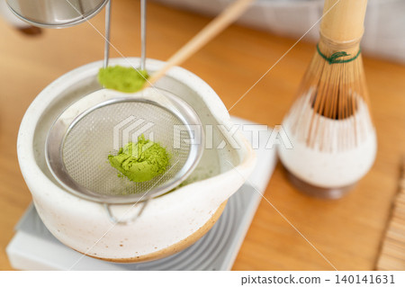 Woman whisking Matcha green tea with bamboo Chasen in bowl 140141631