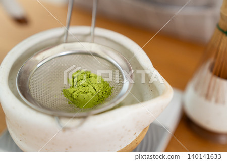 Woman whisking Matcha green tea with bamboo Chasen in bowl Woman whisking Matcha green tea with bamboo Chasen in bowl 140141633