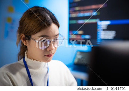 Focused Asian female programmer coding at her office desk Focused Asian female programmer coding at her office desk 140141701