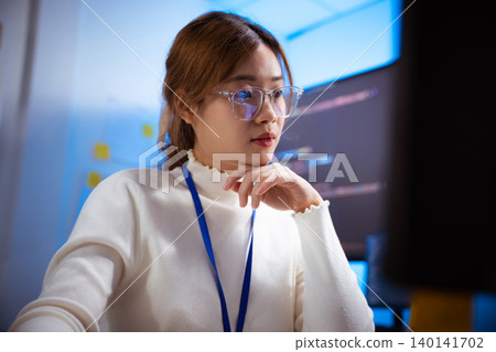 Focused Asian female programmer coding at her office desk Focused Asian female programmer coding at her office desk 140141702